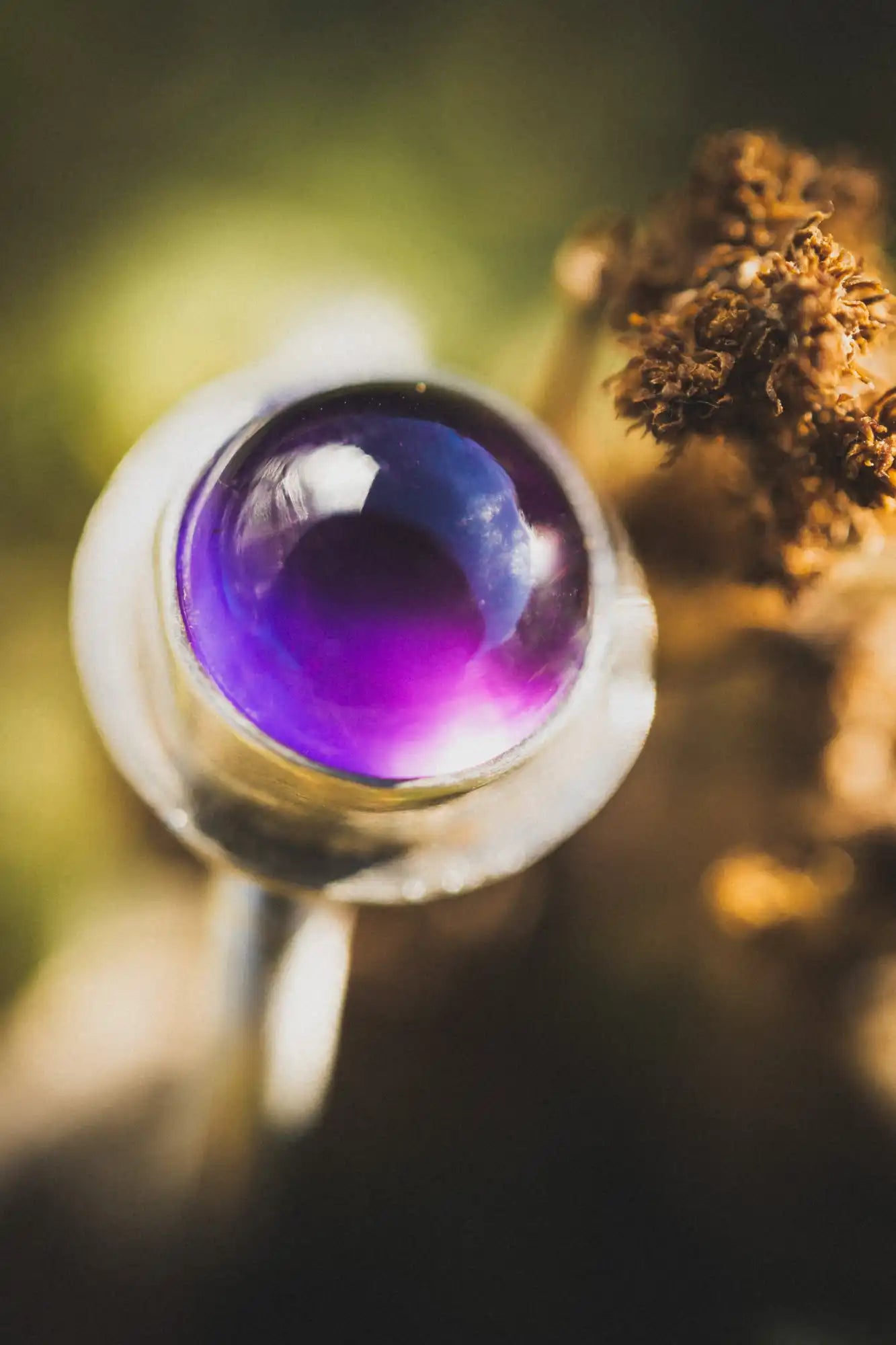 Esfera o mármol de vidrio morado colocado en un anillo metálico.